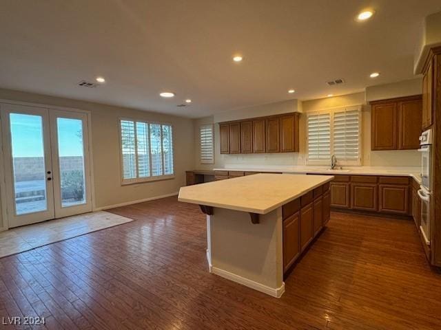 kitchen featuring french doors, dark hardwood / wood-style flooring, a breakfast bar, sink, and a kitchen island