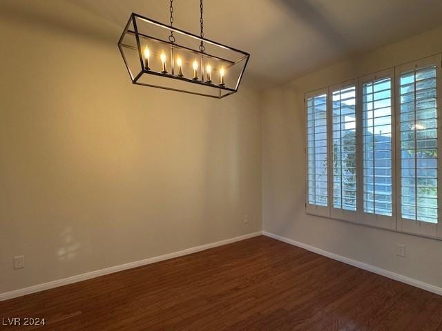 unfurnished room featuring dark hardwood / wood-style floors and an inviting chandelier