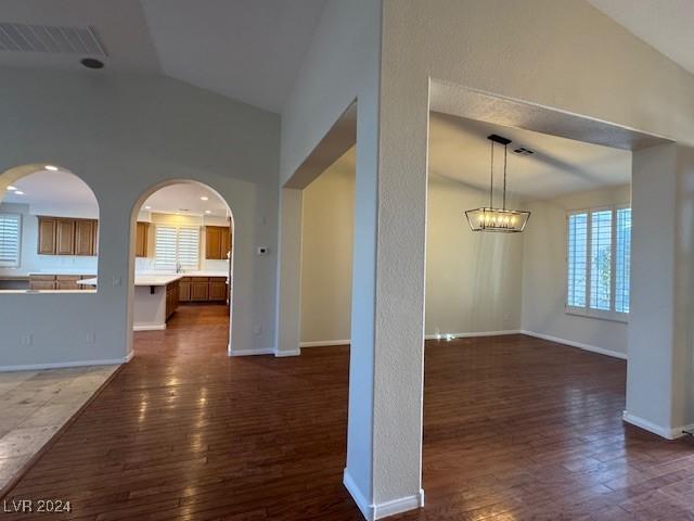 interior space featuring a chandelier, dark wood-type flooring, and vaulted ceiling