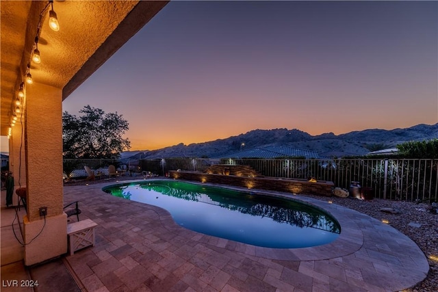 pool at dusk with a mountain view and a patio