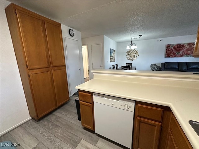 kitchen featuring dishwasher, hanging light fixtures, a textured ceiling, a notable chandelier, and light hardwood / wood-style floors