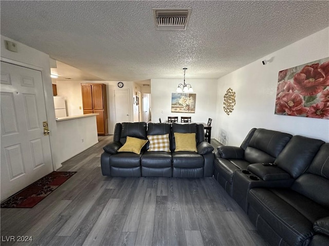 living room featuring a textured ceiling, dark wood-type flooring, and a notable chandelier