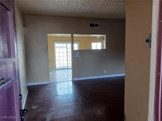 unfurnished room with dark hardwood / wood-style flooring and a textured ceiling