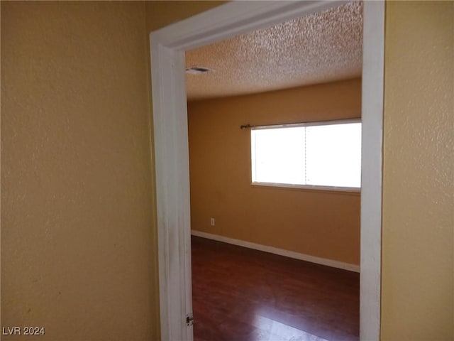 spare room featuring wood-type flooring and a textured ceiling