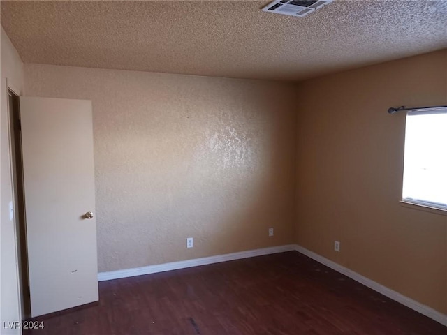 empty room with dark hardwood / wood-style floors and a textured ceiling