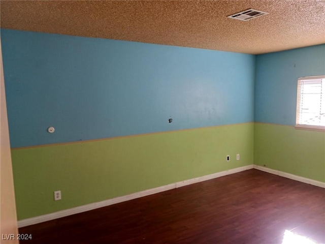 empty room featuring dark hardwood / wood-style flooring and a textured ceiling