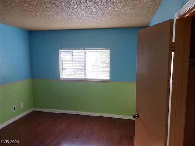 empty room with a textured ceiling and dark wood-type flooring