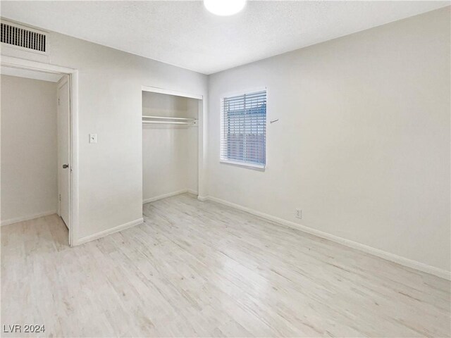 unfurnished bedroom featuring a closet and light hardwood / wood-style floors