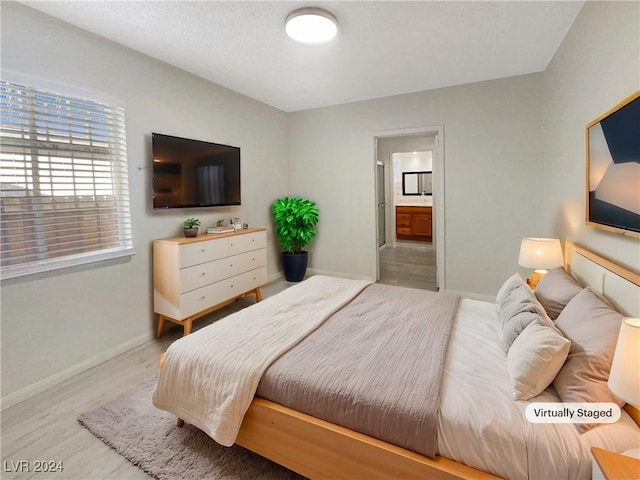 bedroom with ensuite bath and light hardwood / wood-style flooring