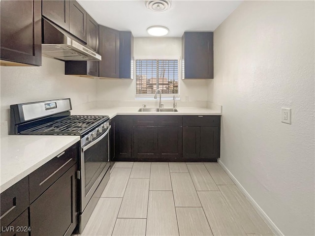 kitchen with dark brown cabinetry, sink, and stainless steel stove