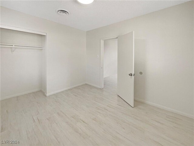 unfurnished bedroom with light wood-type flooring and a closet