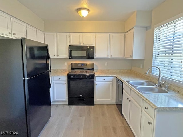 kitchen with white cabinetry, sink, black appliances, and light hardwood / wood-style flooring