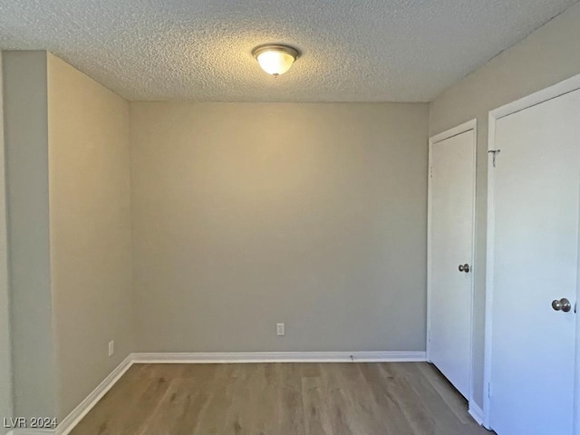 unfurnished room with a textured ceiling and hardwood / wood-style flooring