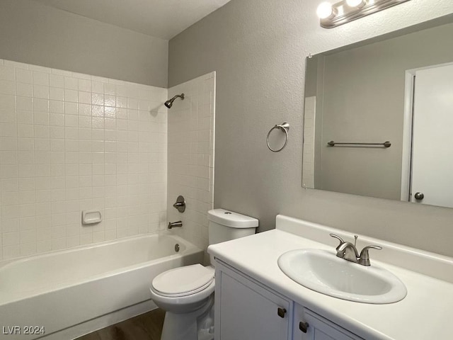 full bathroom featuring hardwood / wood-style flooring, vanity, tiled shower / bath combo, and toilet