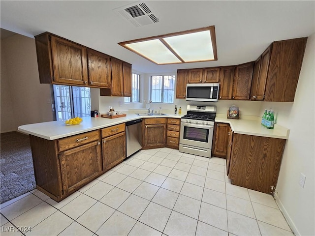 kitchen with kitchen peninsula, sink, light tile patterned floors, and appliances with stainless steel finishes