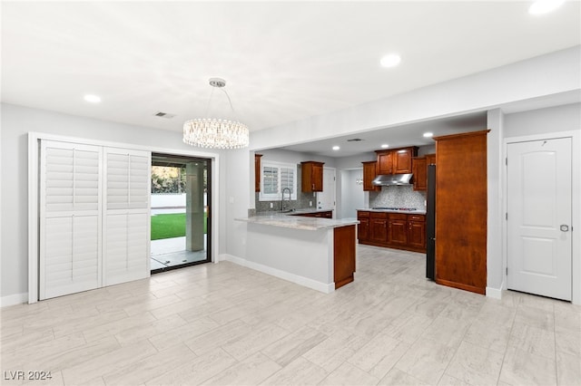 kitchen featuring pendant lighting, backsplash, sink, kitchen peninsula, and a chandelier