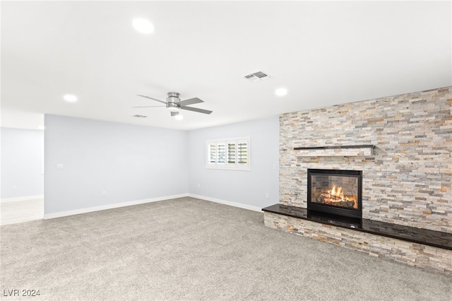 unfurnished living room featuring carpet flooring, ceiling fan, and a stone fireplace