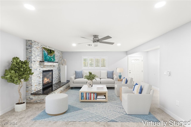 carpeted living room with ceiling fan and a fireplace