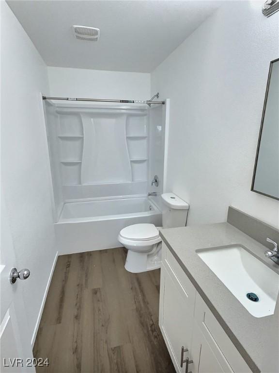 full bathroom with hardwood / wood-style floors, vanity, toilet, and tub / shower combination