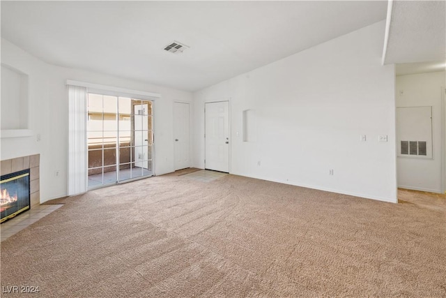 unfurnished living room featuring a tile fireplace, light carpet, and lofted ceiling