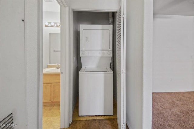 clothes washing area with carpet flooring, sink, and stacked washer and clothes dryer