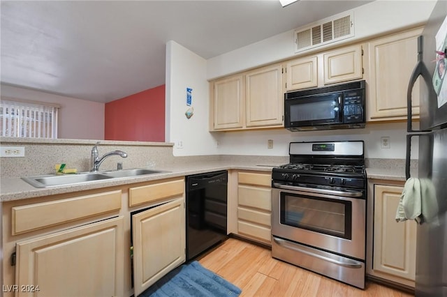 kitchen with sink, black appliances, and light wood-type flooring