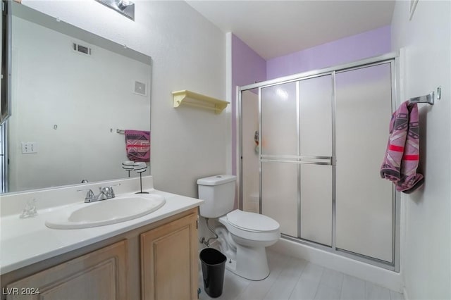 bathroom featuring vanity, a shower with shower door, and toilet