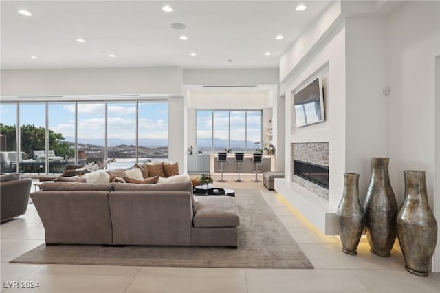 living room with a stone fireplace and light tile patterned flooring