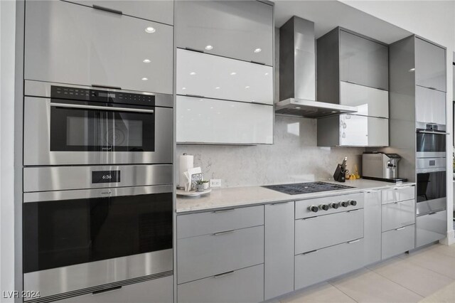 kitchen with double oven, wall chimney exhaust hood, tasteful backsplash, gray cabinetry, and white gas stovetop