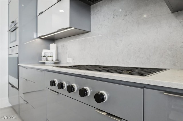 kitchen with white oven, white cabinetry, and cooktop