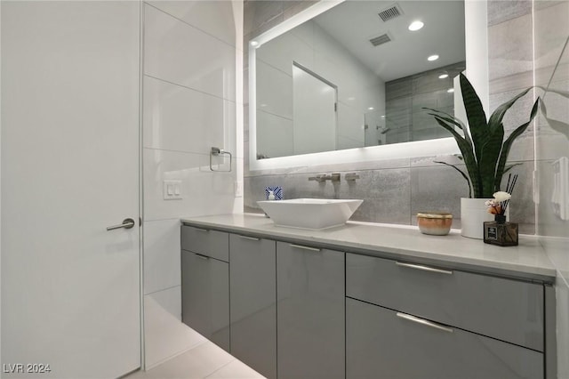 bathroom with a shower with shower door, vanity, and tasteful backsplash