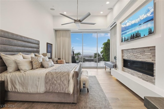 bedroom featuring ceiling fan, light hardwood / wood-style flooring, access to outside, and a fireplace