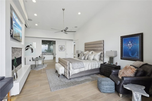 bedroom featuring ceiling fan, a stone fireplace, and lofted ceiling