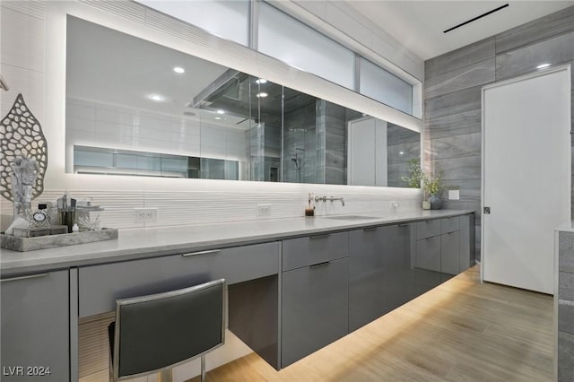 bathroom with wood-type flooring, an enclosed shower, vanity, and tile walls