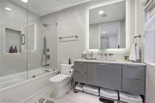 full bathroom with tile patterned flooring, vanity, tile walls, toilet, and combined bath / shower with glass door