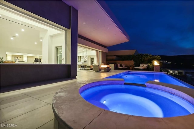 pool at twilight with an in ground hot tub and a patio