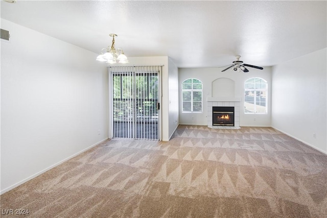 unfurnished living room with a tiled fireplace, light colored carpet, and ceiling fan with notable chandelier