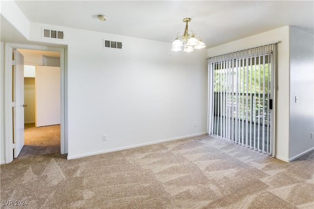 spare room featuring carpet flooring and a chandelier