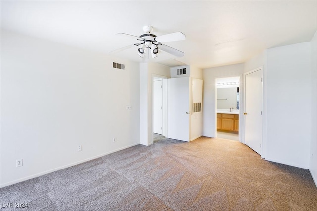 unfurnished bedroom with light colored carpet, ensuite bath, ceiling fan, and sink