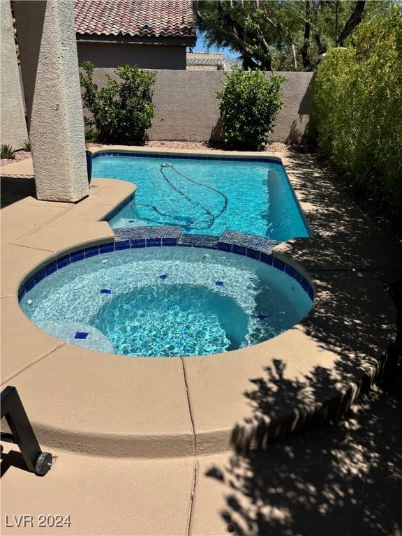 view of swimming pool with an in ground hot tub