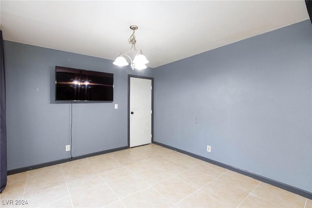 empty room with light tile patterned floors and a chandelier