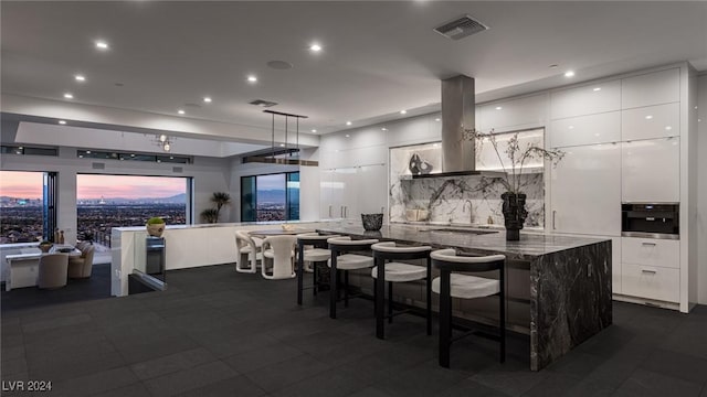 kitchen with backsplash, extractor fan, decorative light fixtures, a kitchen bar, and white cabinets