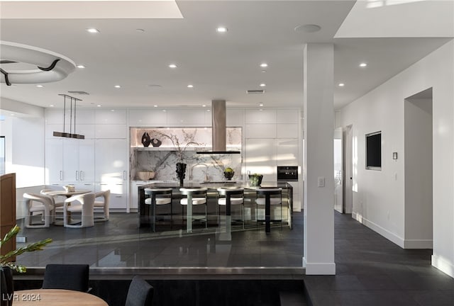 kitchen with white cabinetry, hanging light fixtures, a kitchen island, and exhaust hood