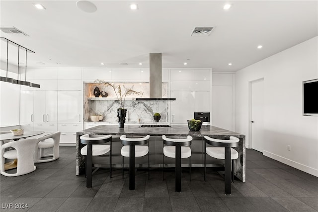 kitchen featuring ventilation hood, a kitchen breakfast bar, an island with sink, white cabinetry, and gas cooktop