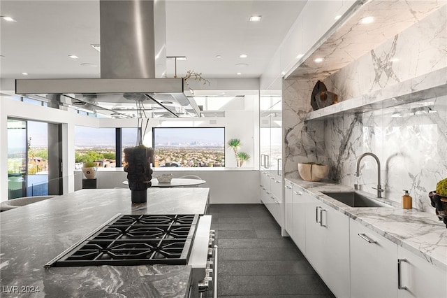 kitchen featuring white cabinetry, sink, gas cooktop, light stone counters, and decorative backsplash