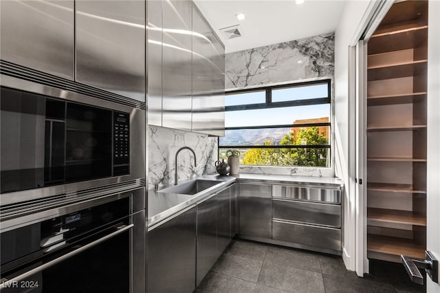 kitchen with a mountain view, backsplash, sink, appliances with stainless steel finishes, and stainless steel counters