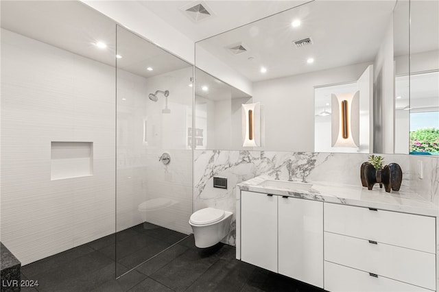 bathroom with tile patterned floors, a tile shower, vanity, tile walls, and toilet