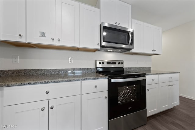 kitchen with dark hardwood / wood-style floors, dark stone countertops, white cabinetry, and stainless steel appliances