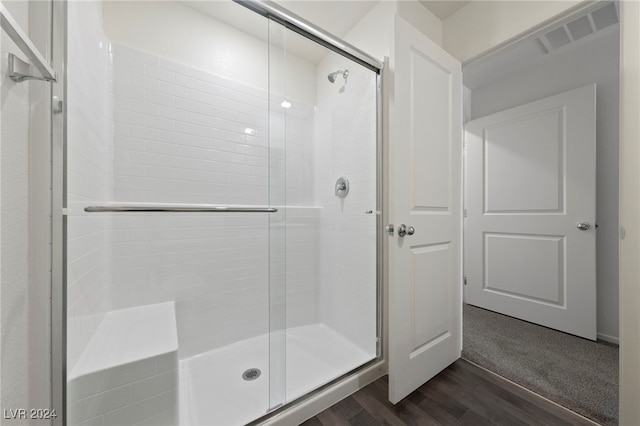 bathroom with hardwood / wood-style floors and a shower with shower door