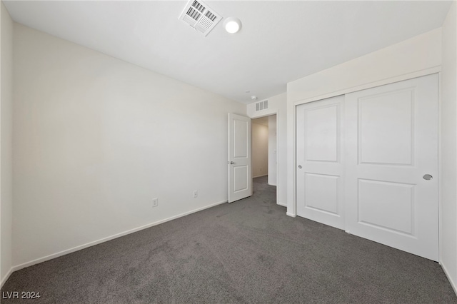 unfurnished bedroom featuring dark carpet and a closet